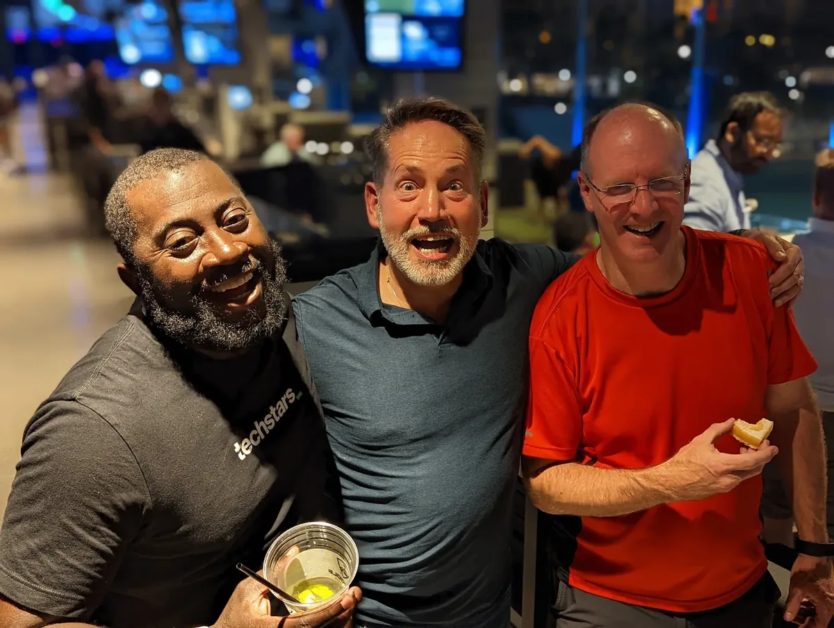 Three industry colleagues laughing together at an evening event.